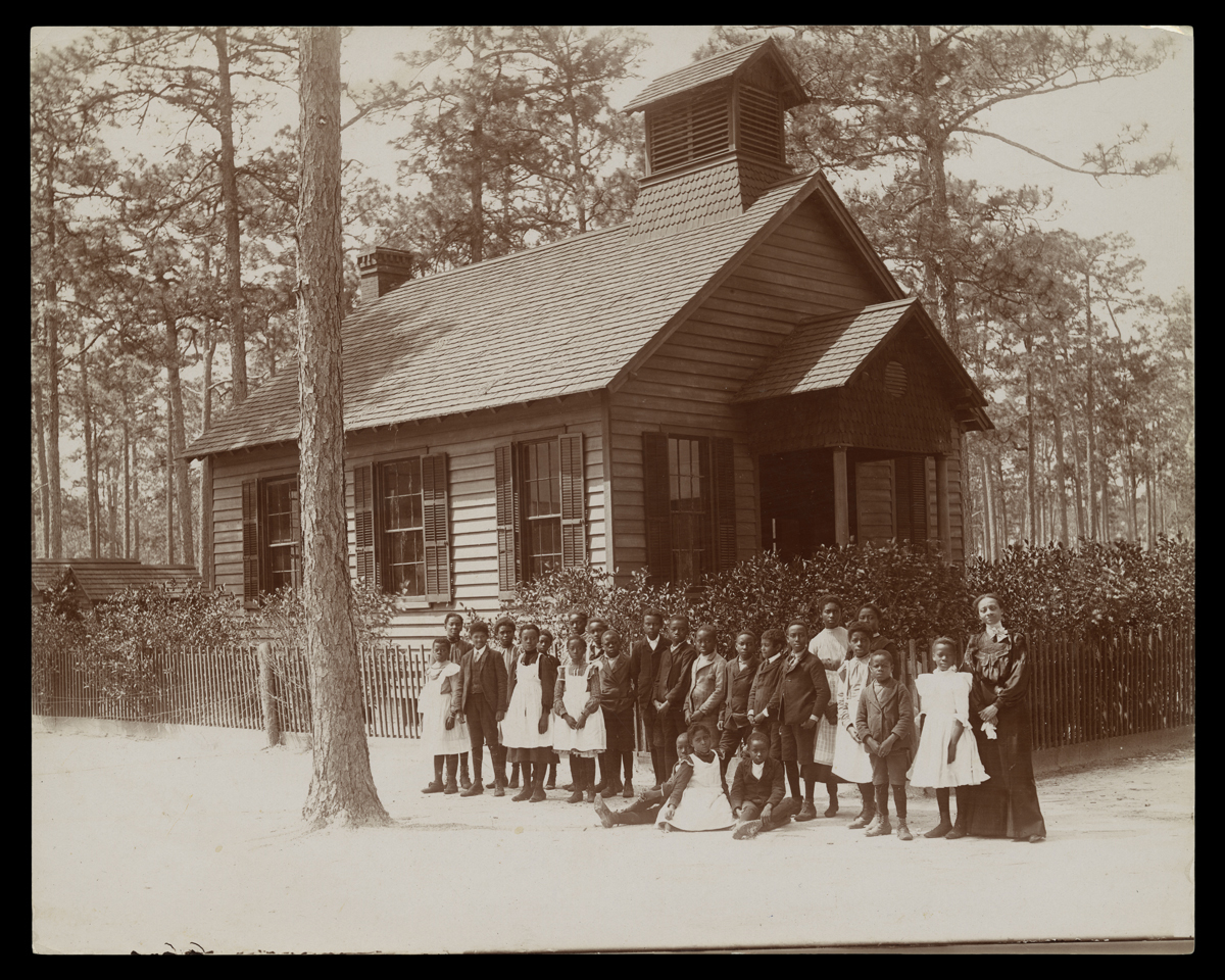 School Teacher and Her Students, Pinehurst Tea Plantation, Summerville, South Carolina, circa 1903 Black-and-white photo of group of African American boys and girls standing with an African American woman outside a small wooden building