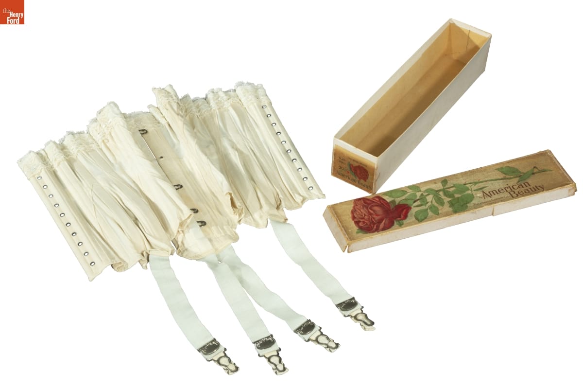 Kalamazoo Corset Company "American Beauty Style 626" Corsets, 1891-1922 White corset with hook-and-eyes and belts with clips hanging down, next to box with image of red rose and text "American Beauty"