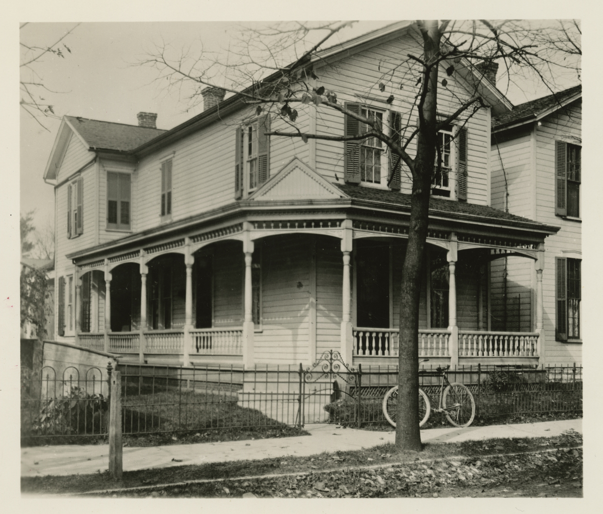 Wright Home, Original Site, Dayton, Ohio, circa 1900 Outside view of two-story house with wrap-around porch and bicycle propped against fence