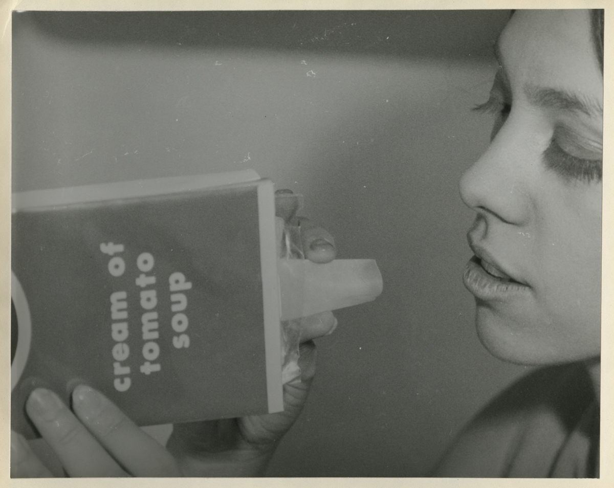 Woman holds box labeled "cream of tomato soup" with plastic spout to her mouth