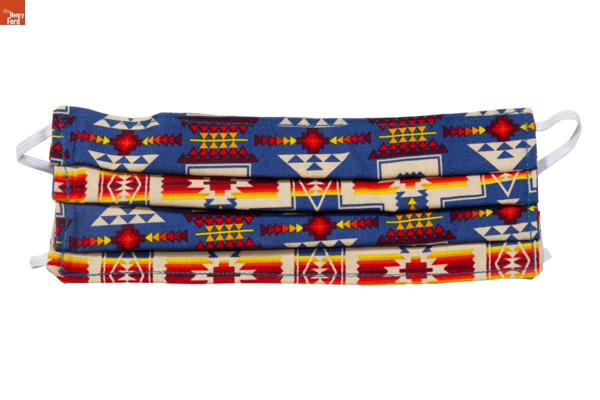 Pleated fabric face mask with geometric pattern in blue, white, yellow, and red