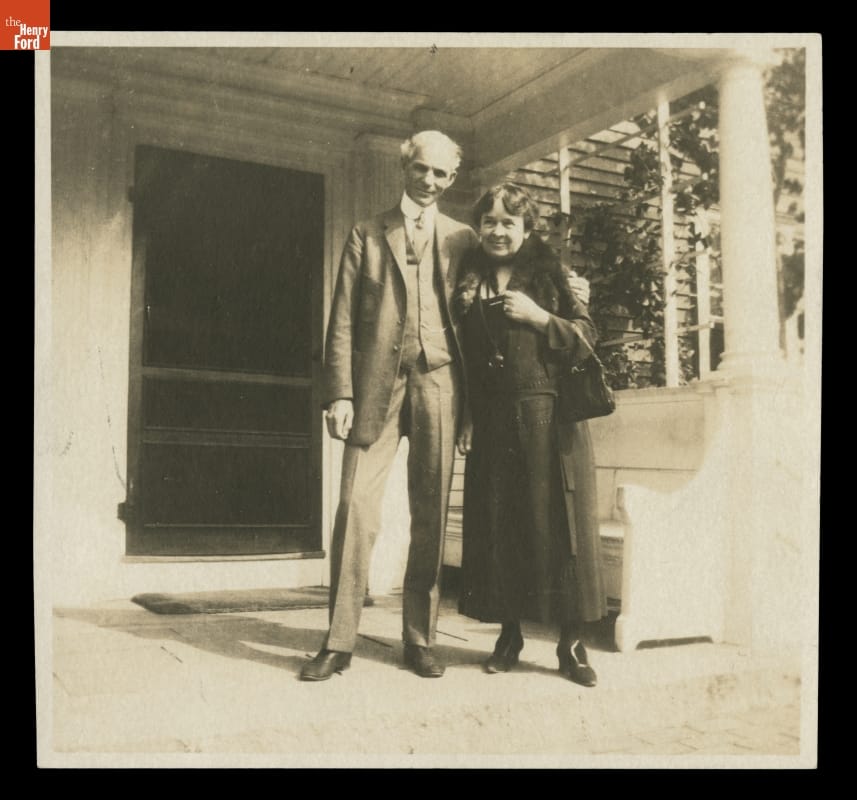 Henry Ford and Clara Ford at the Wayside Inn, Sudbury, Massachusetts, circa 1923 Black-and-white photo of man and woman standing on the porch of a building