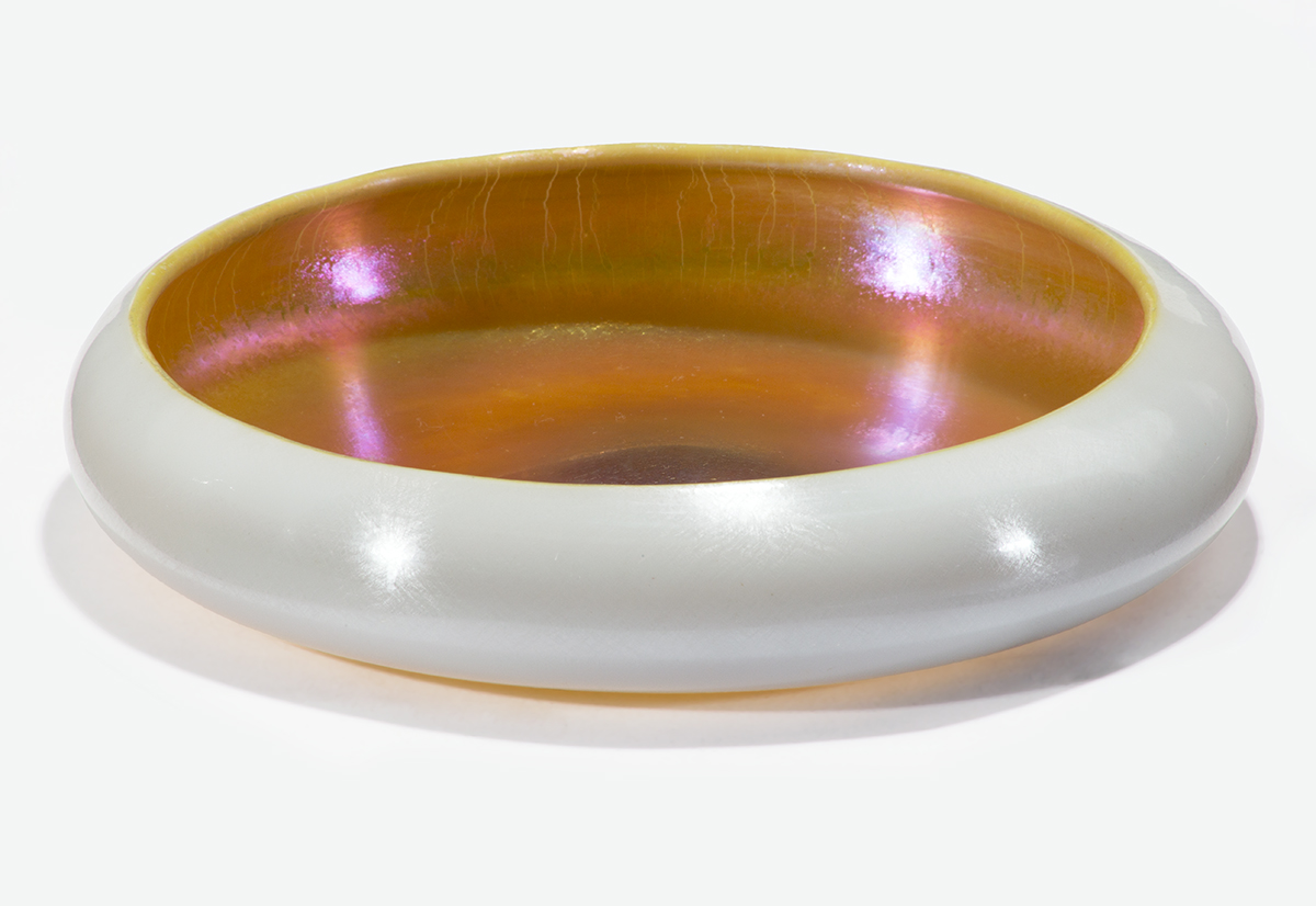 Low, round glass bowl; white on outside, iridescent amber/gold on inside