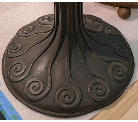 GIF rotating through two photos of round lamp base with swirled pattern; the first is dark and dull and the second is lighter and shiny