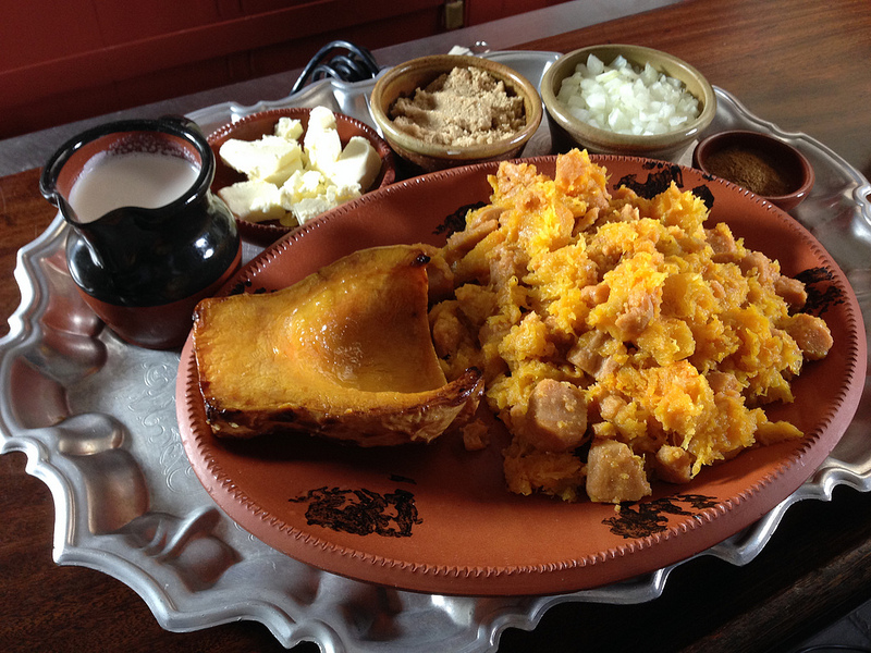 A silver tray holds ceramic dishes with roasted squash, milk or cream, butter, and other ingredients