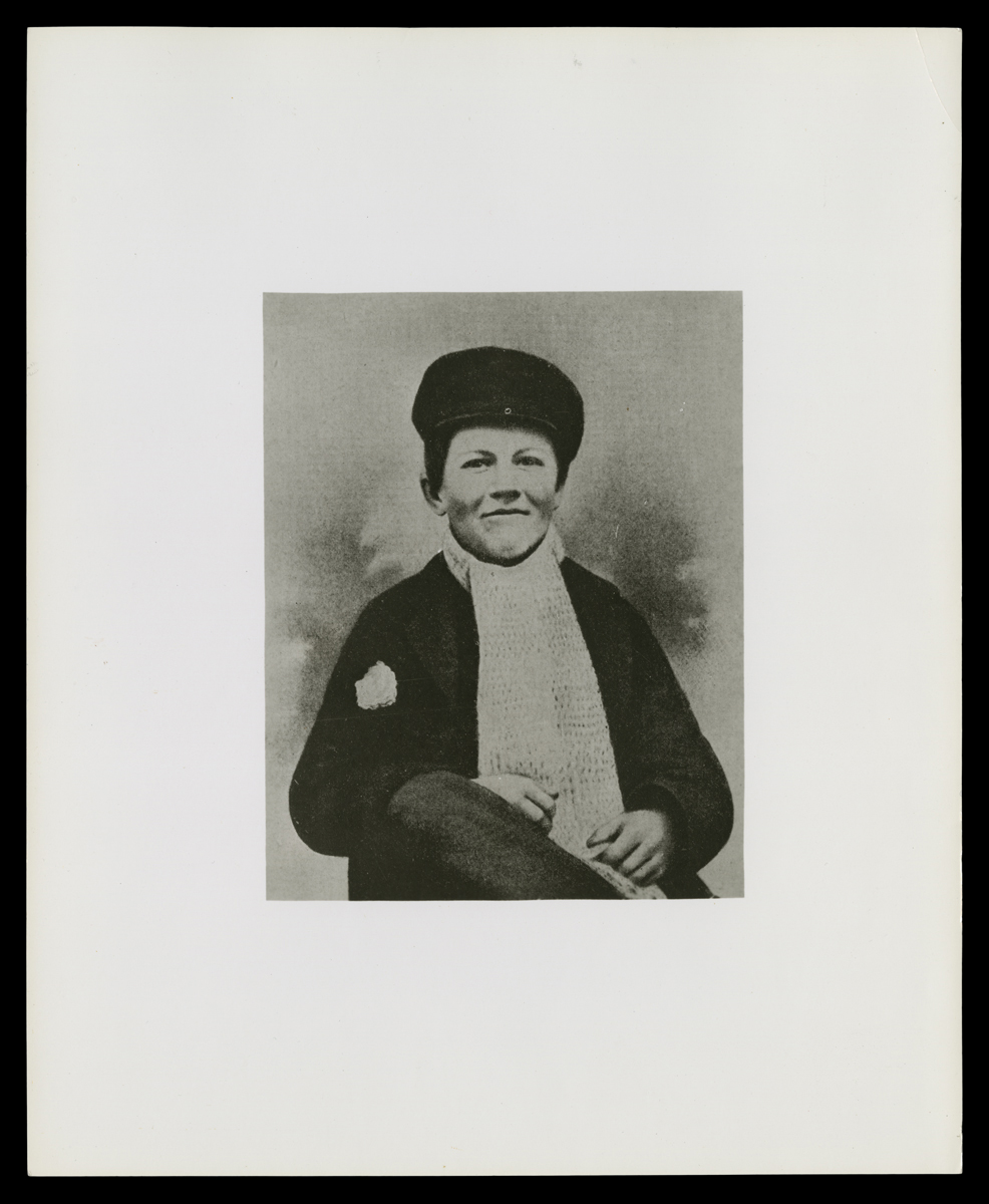 Thomas A. Edison as a Newsboy and Candy Butcher, circa 1861 Black-and-white photo of seated young boy in hat, scarf, and jacket