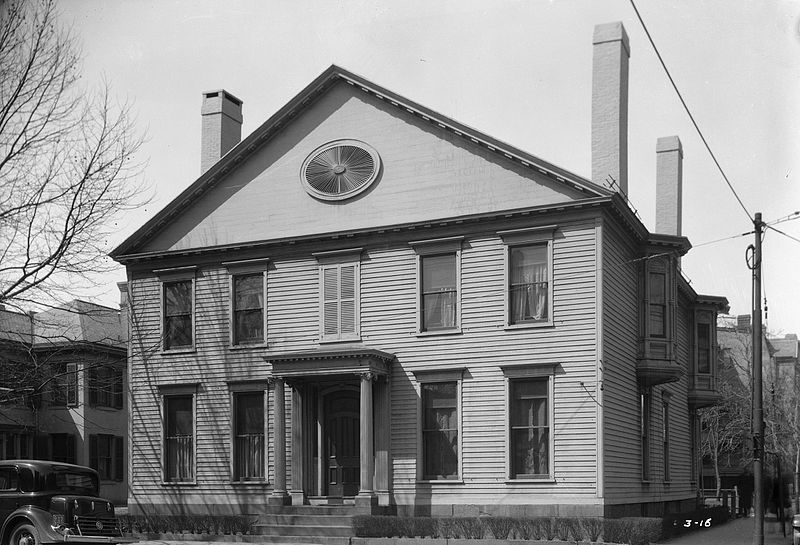 Black-and-white photo of two-story wooden house with columns flanking front door