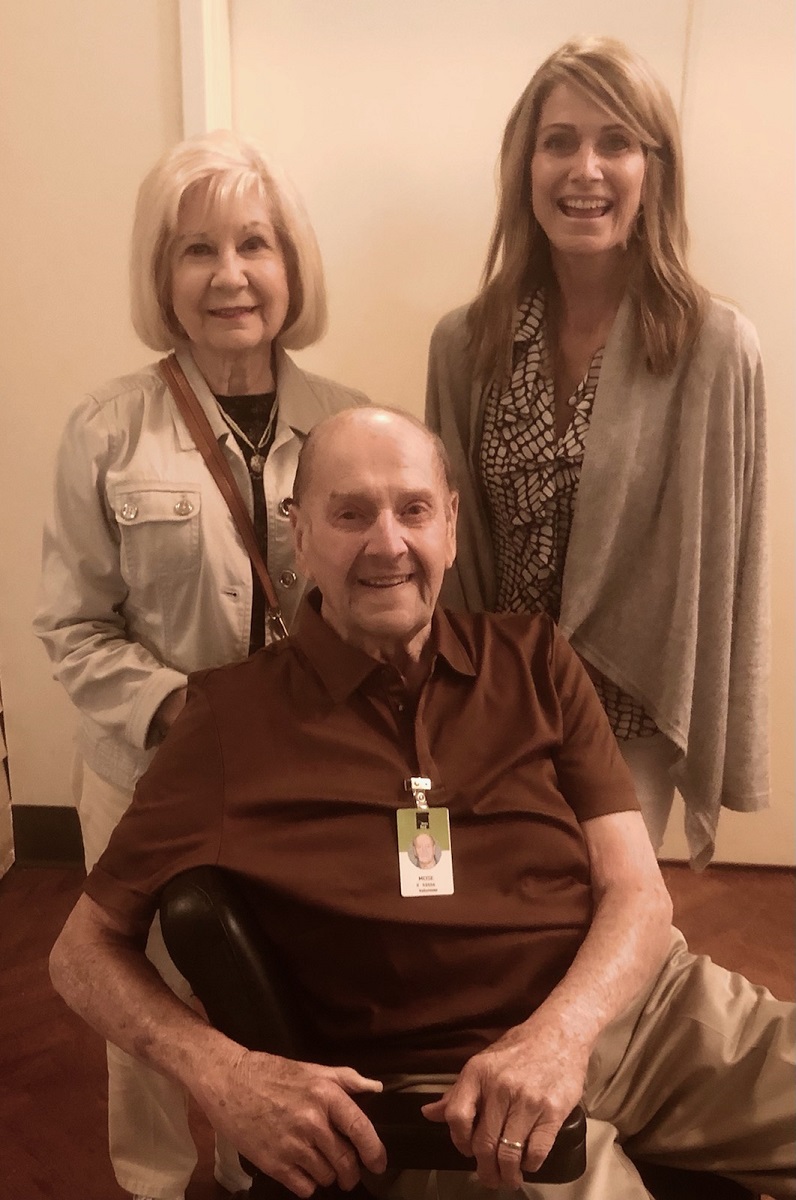 Seated man with two women standing behind him
