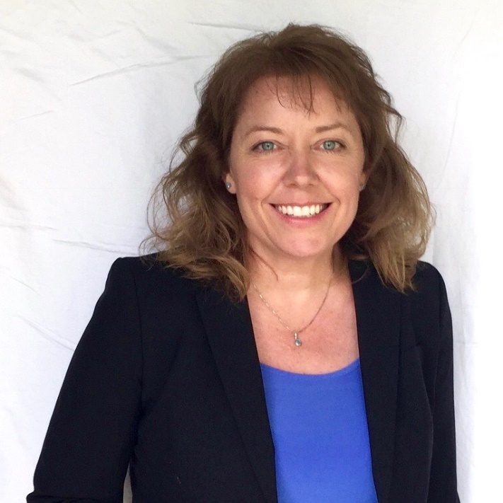 Medium-light-skinned woman with brown hair in blue shirt and black blazer