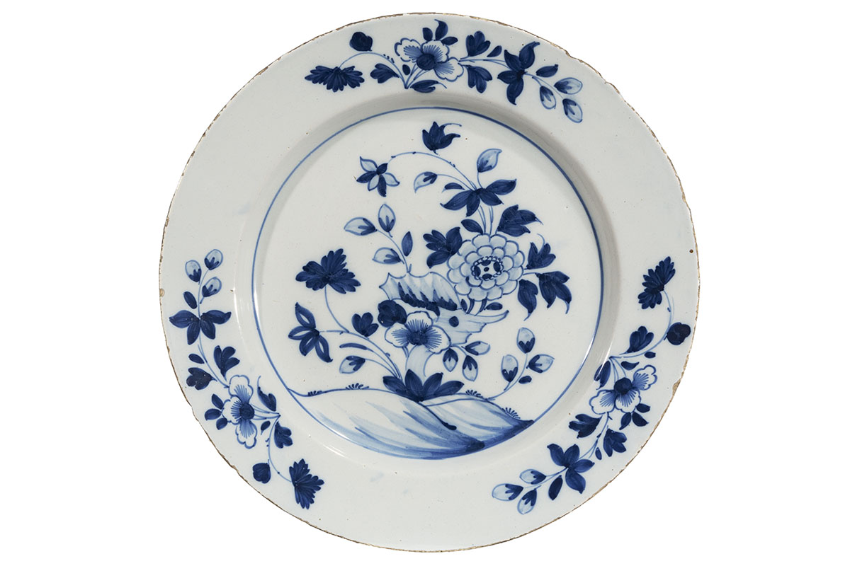 White plate with blue floral decorations in three places on rim and large blue floral decoration in center