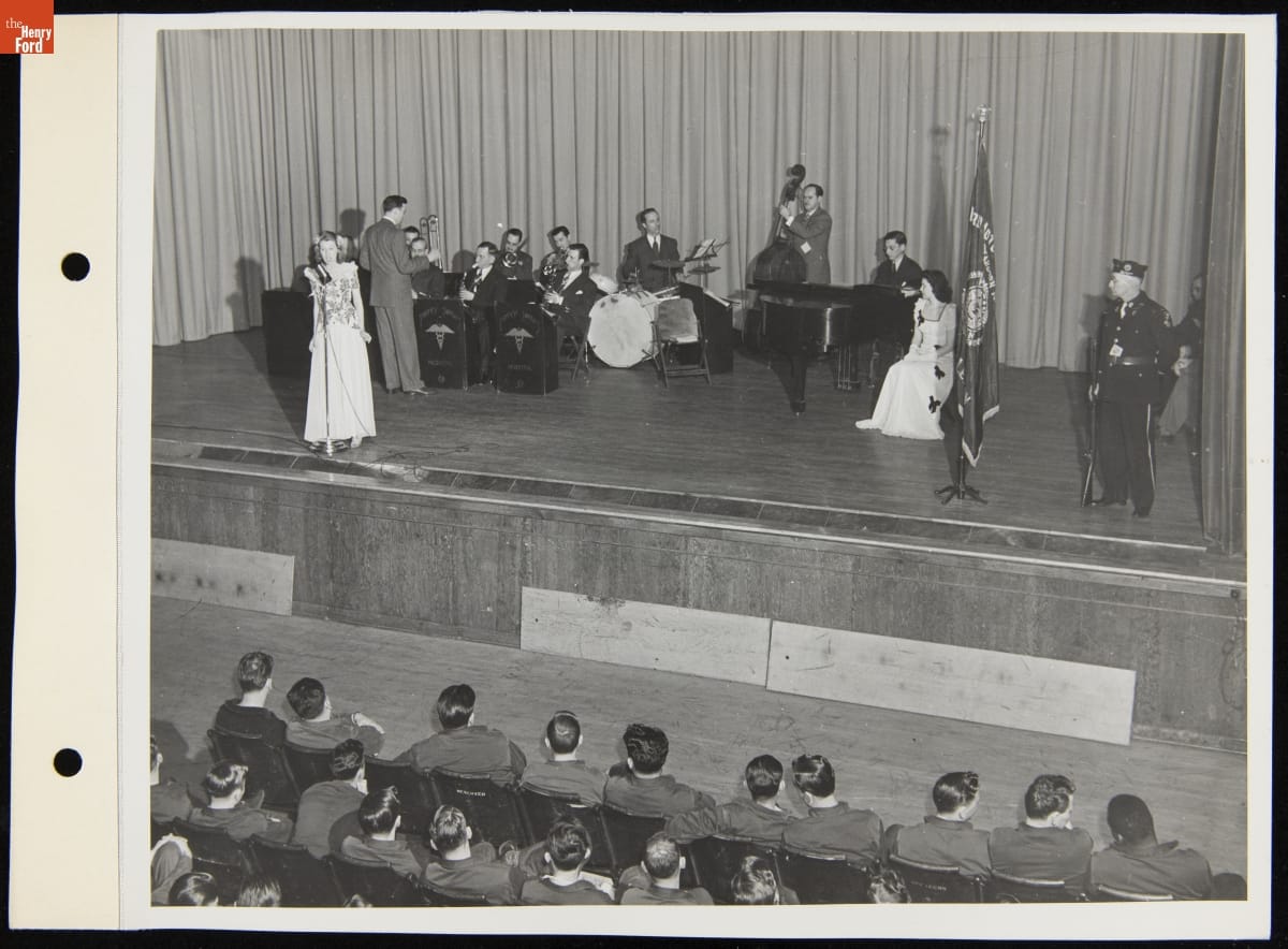 Band Entertaining Soldiers at Percy Jones Hospital, Battle Creek, Michigan, April 1944 Men with instruments and two women, one at a microphone, on a stage with a soldier in front of an audience