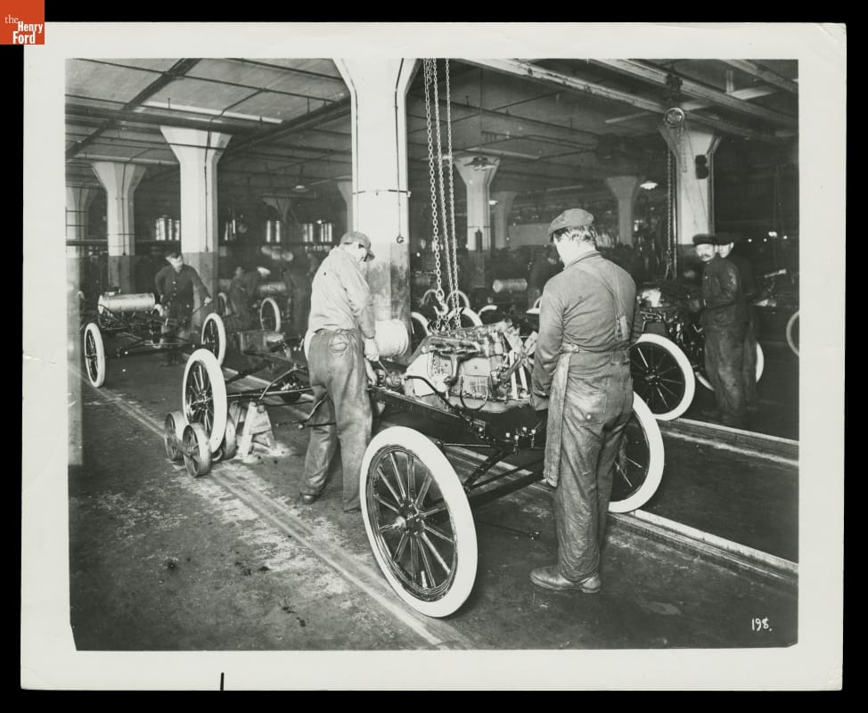 People work on car bodies in factory
