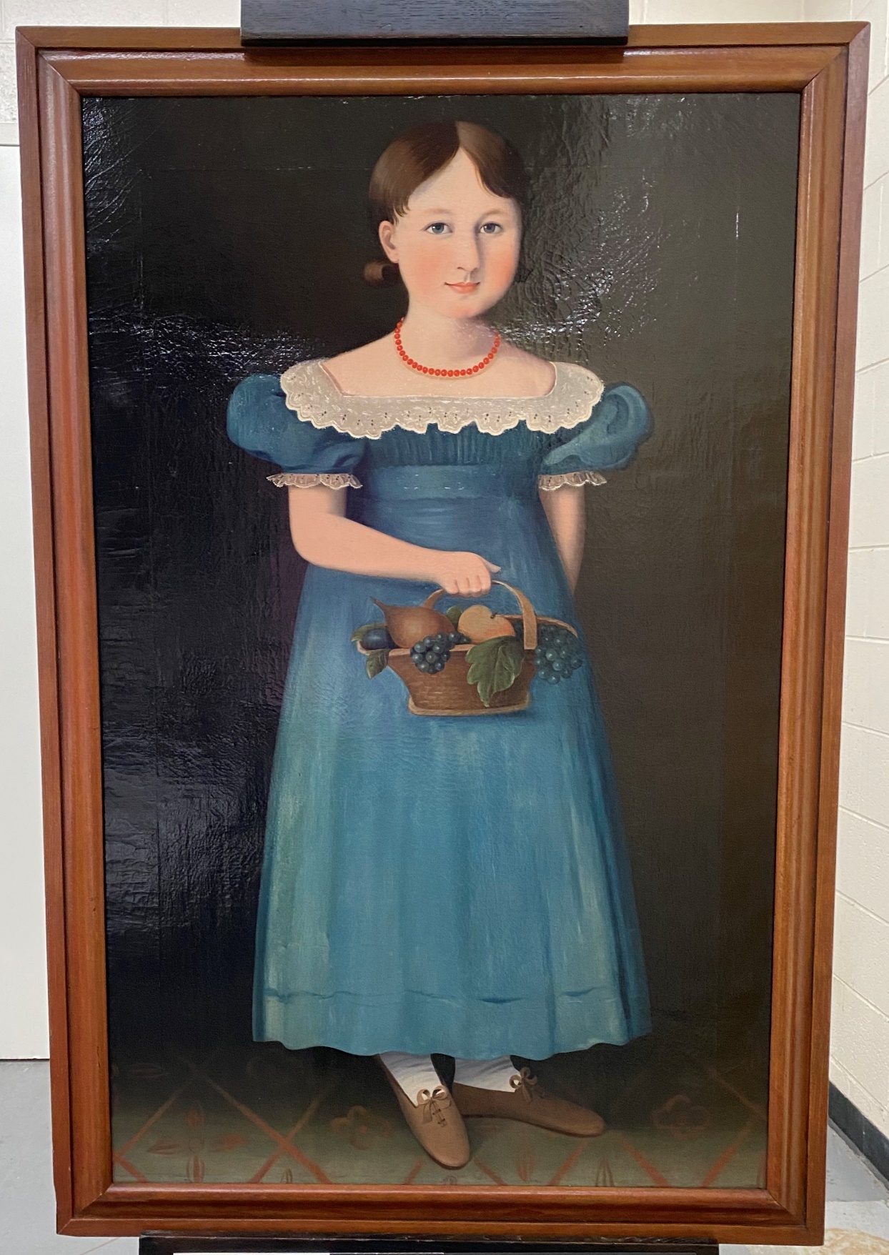 Framed painting of girl in blue dress holding basket of fruit
