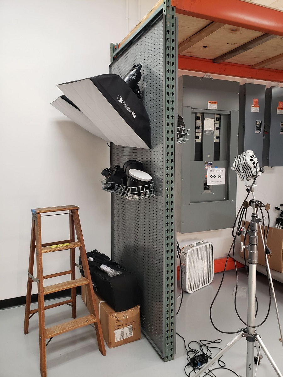 Pallet rack and pegboard Pallet racking with lights hanging from it and a ladder on one side, and electrical boxes on the other side