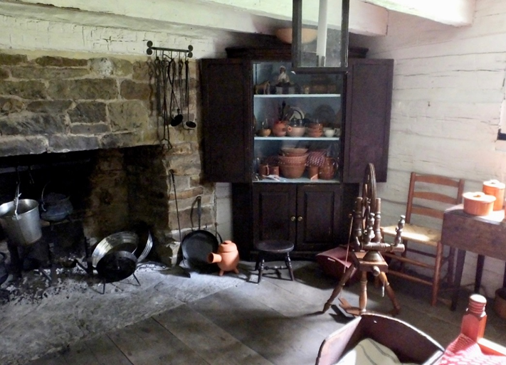 Room interior showing large stone fireplace and a variety of old-fashioned furnishings