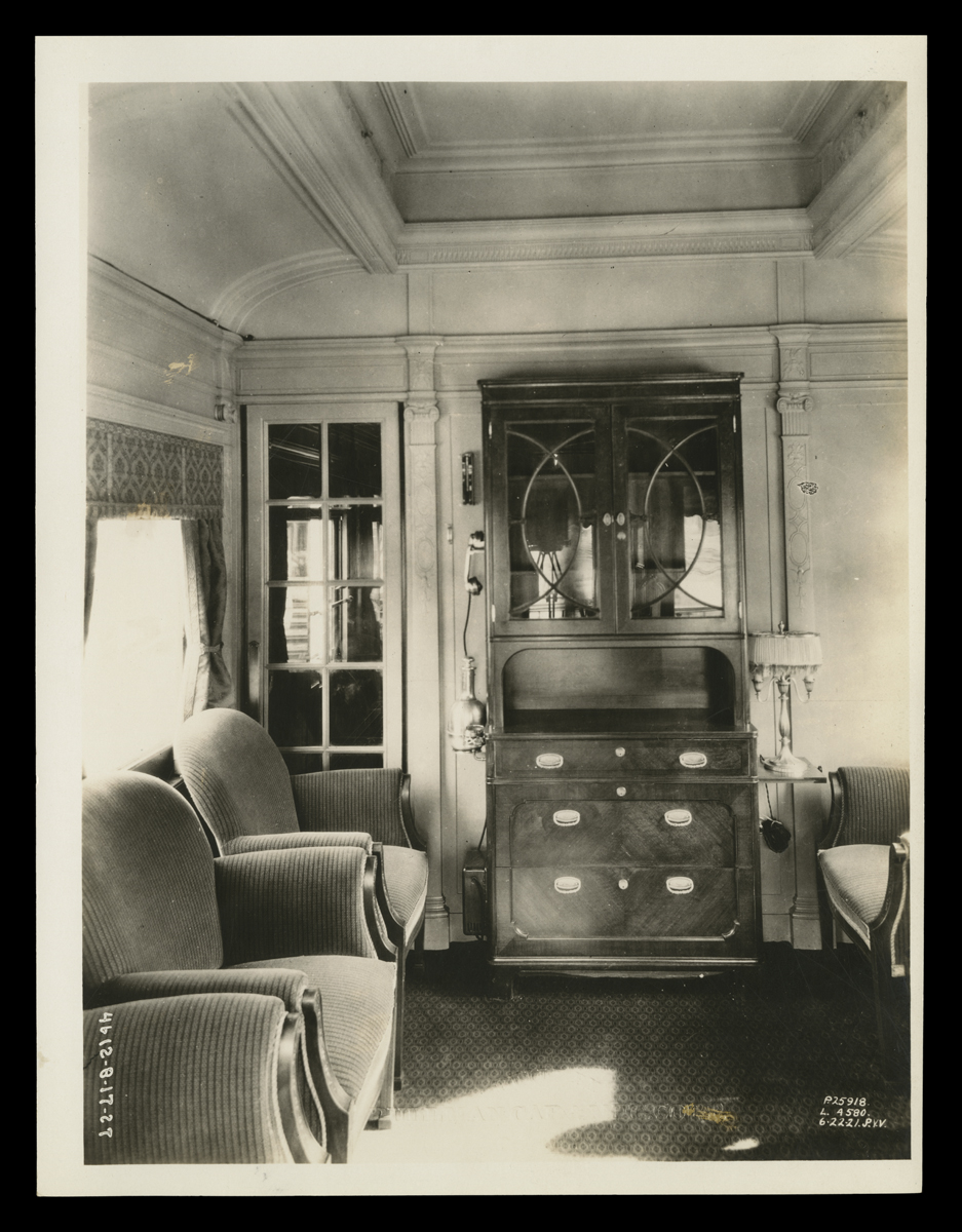 Interior of room with two upholstered chairs and dresser with cabinet above