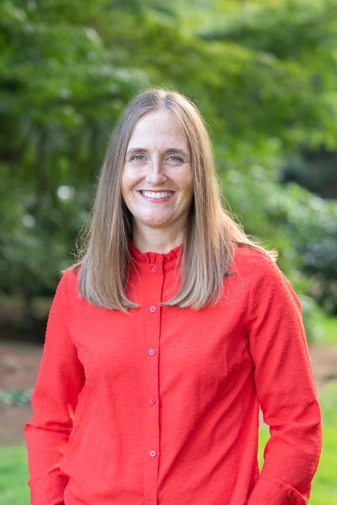 Kristin Barrus. Image of woman with long blonde hair in a long-sleeved red shirt.