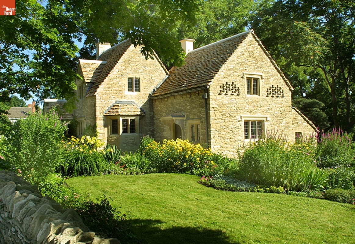 Stone house with green lawn and lush flower garden