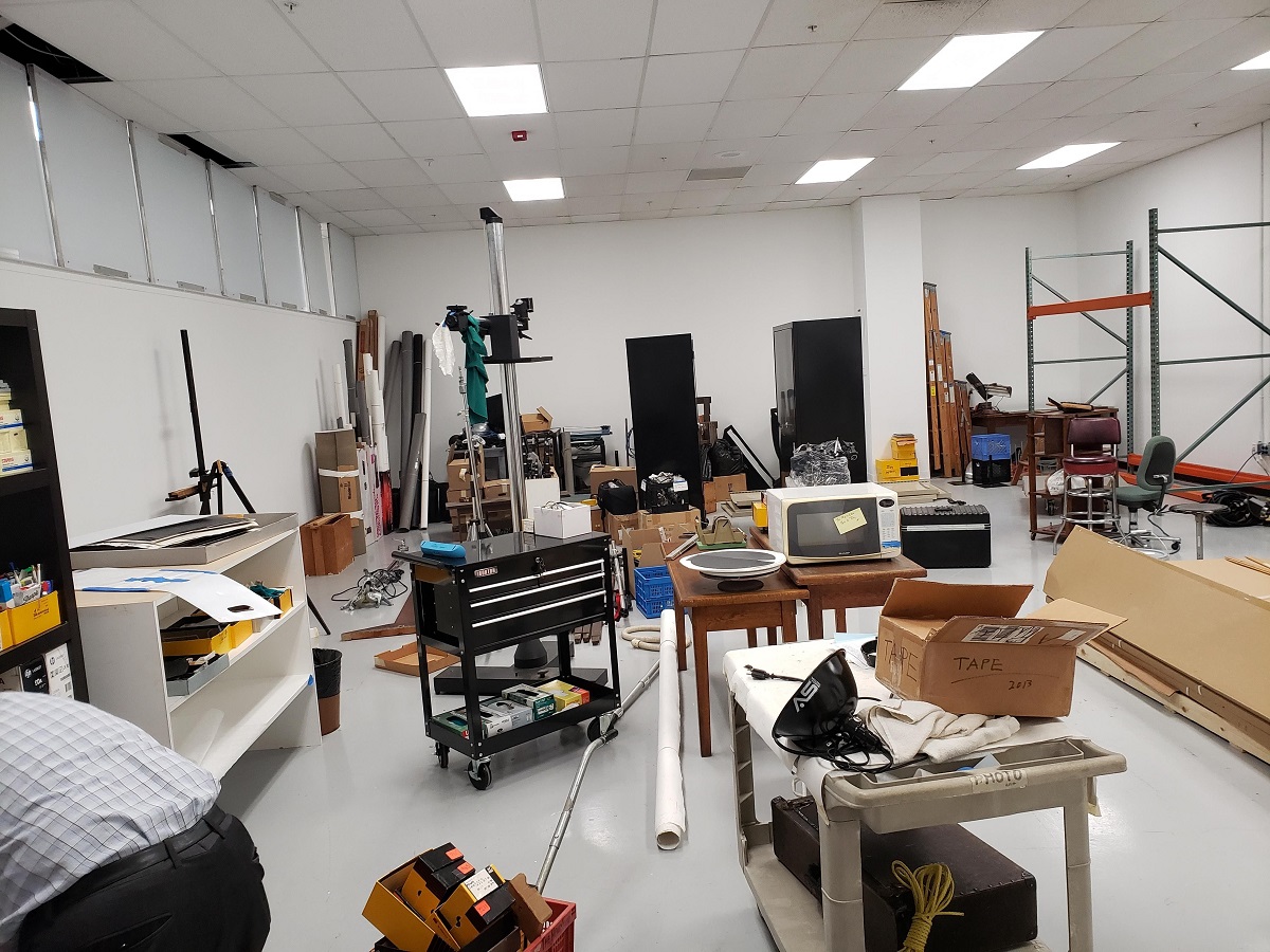 Unpacking and rearranging the new Photo Studio Cluttered room filled with carts, furniture, and other items