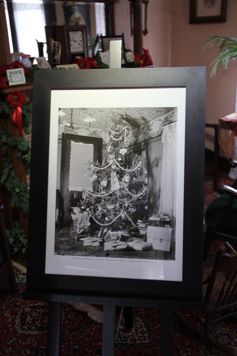Large framed black-and-white photograph showing a Christmas tree on an easel in a room