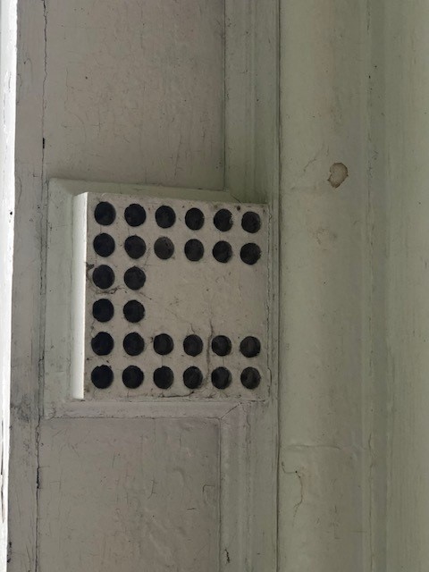 Architectural element of white box with round holes in a "U" pattern in it