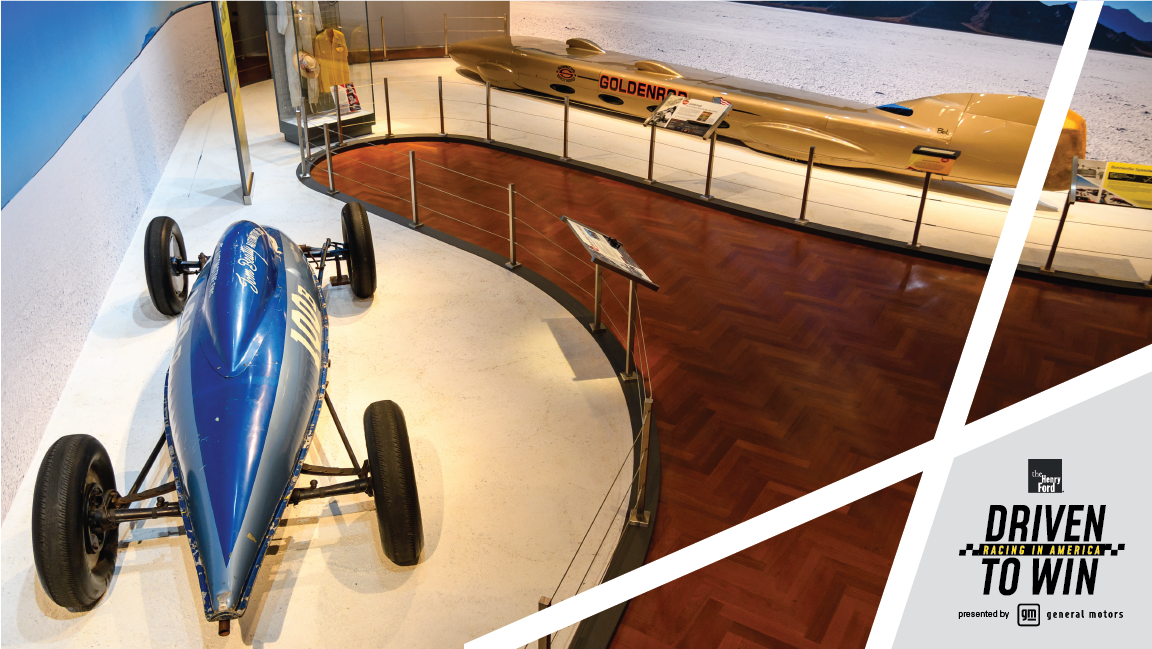 The 1965 Goldenrod Land Speed Race Car and the 1951 Beatty Belly Tank Lakester Land Speed Race Car in Driven to Win Aerial view of museum exhibit featuring very long, low gold race car and short, squat teardrop-shaped race car in two shades of blue
