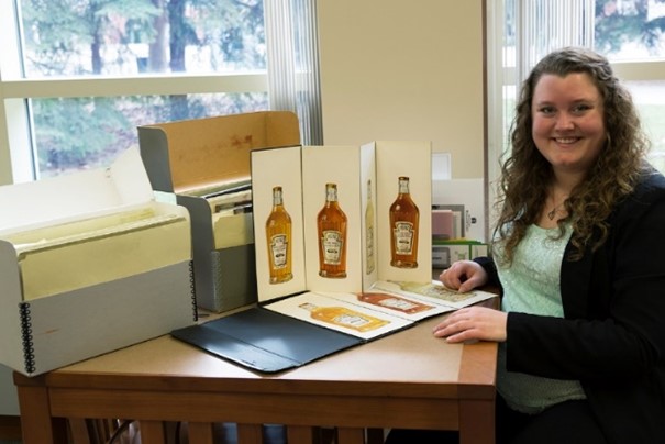 Woman sitting at table with boxes and images both standing up and lying flat