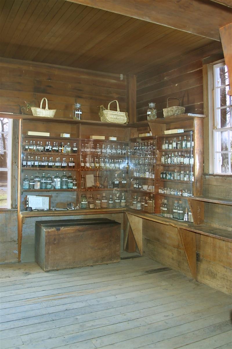 Corner of room with shallow wood shelves filled with baskets, bottles, and jars
