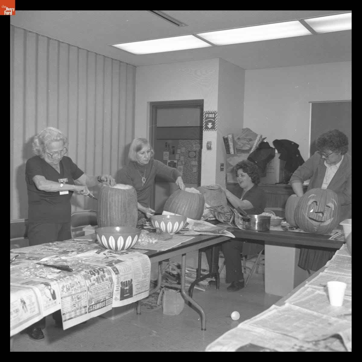 Volunteers Carving Pumpkins for Family Halloween Jamboree in Greenfield Village, October 1981 Four women carve pumpkins on tables covered in newspaper