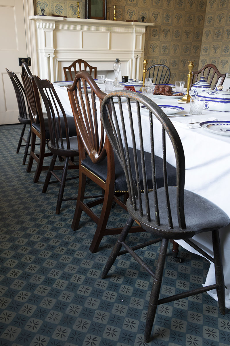 Mismatched chairs along side of table; fireplace in background