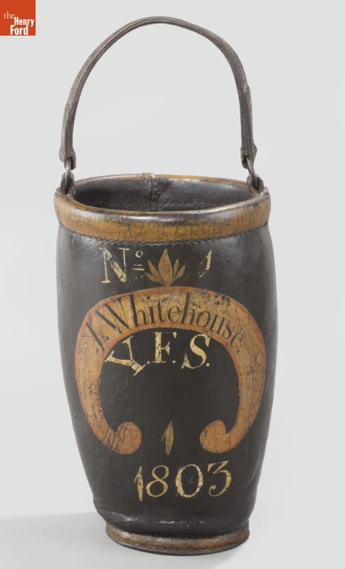 Tall, narrow, black leather bucket with a handle, with writing and decoration on side