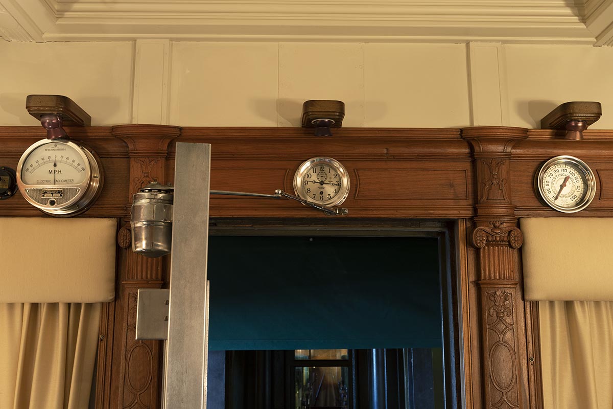 Part of interior wall with wood paneling, doorway, and three silver clocks/dials