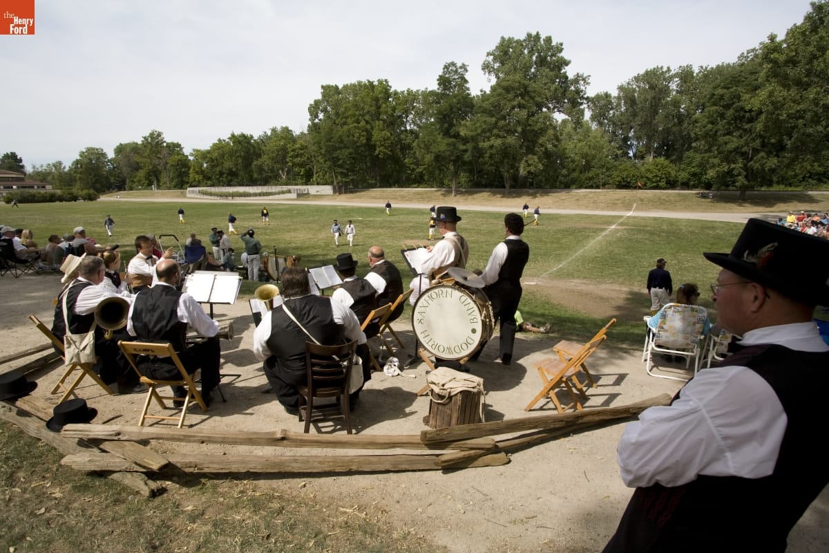 World Tournament of Historic Baseball in Greenfield Village, August 2007 A group of people with musical instruments sit and stand in a circle next to a baseball field and spectators