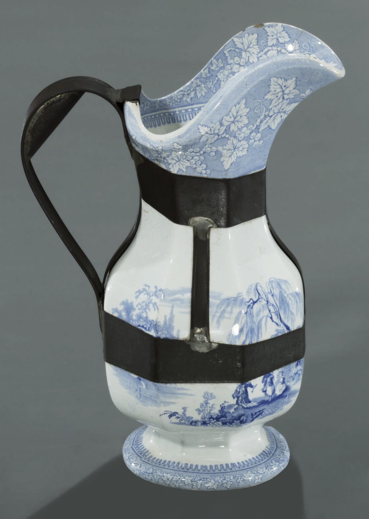 Photograph of a ceramic pitcher that has been reinforced by a tinsmith with a metal structure