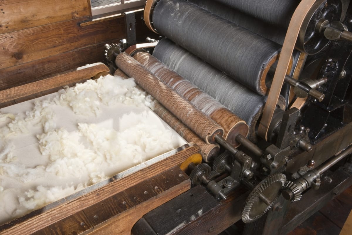 Carding Machine, 1850-1880 Fluffy white wool rests on a conveyor belt heading toward a machine with multiple rollers
