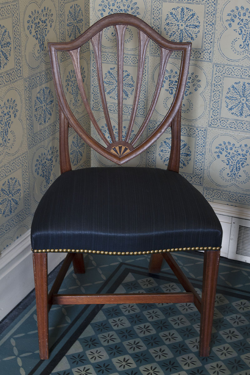 Wooden chair with back slats in shield shape and dark blue satin seat