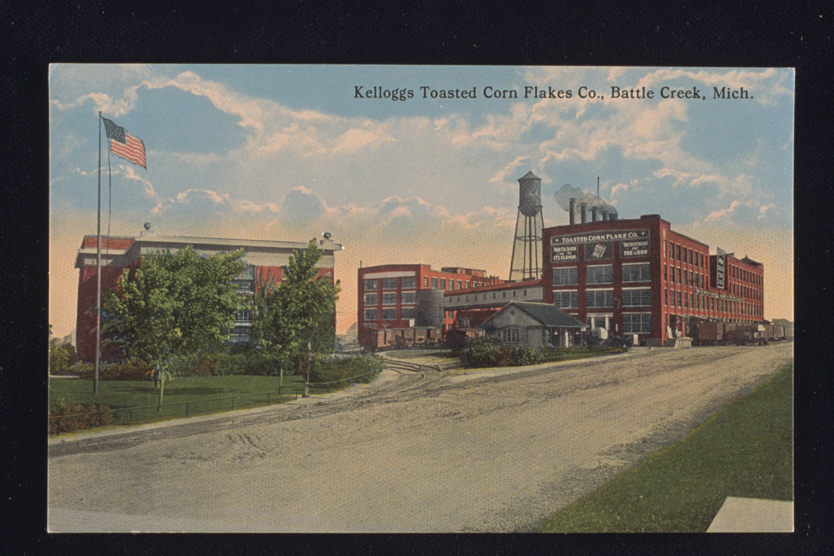 Kelloggs Toasted Corn Flakes Company, Battle Creek, Michigan, 1914 Postcard of Kellogg’s Toasted Corn Flake Company factory, 1914, showing several red brick buildings, a water tower, and an American flag in the foreground