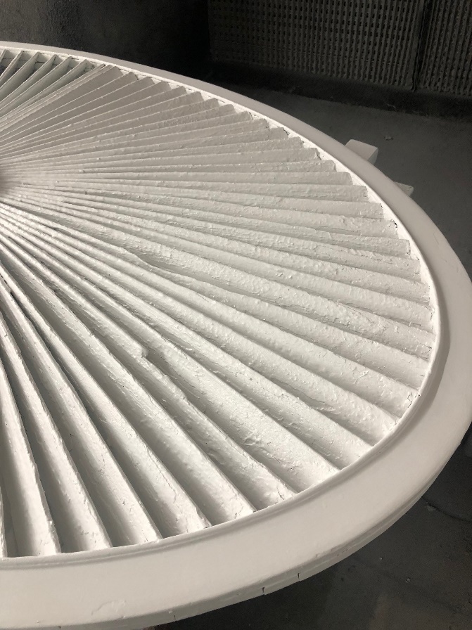 Close-up of round wooden architectural element with fan-shaped tines