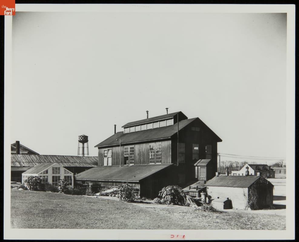 Large wooden building with greenhouse and other buildings nearby