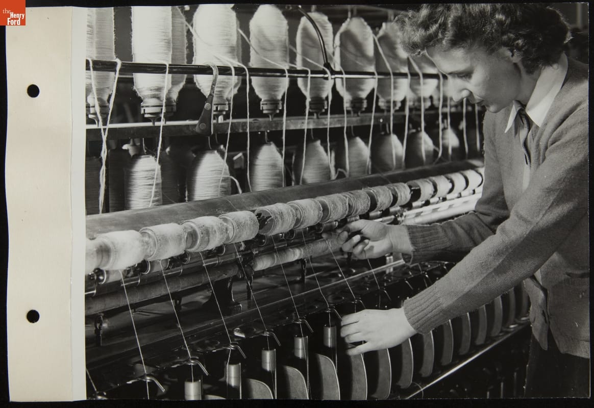 Woman works at machine set up with many spools of yarn
