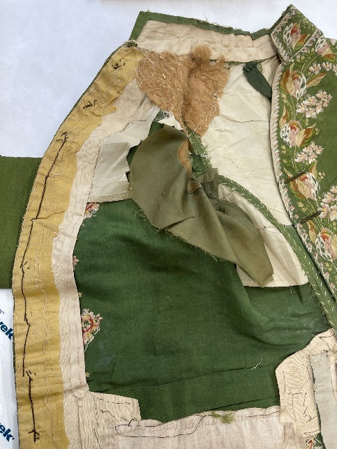 Buckram stiffens the inside of the front of the coat A coat interior lies flat on a table, revealing a patchwork of fabrics and stitching inside