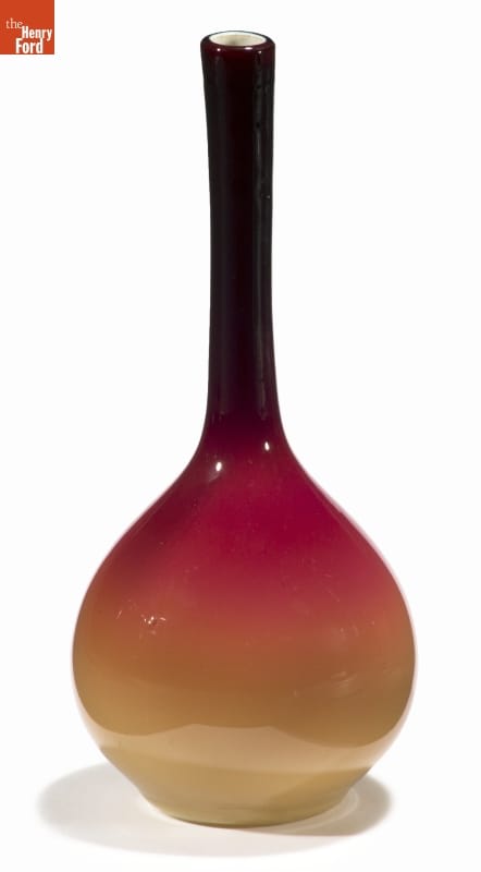 Vase with round body and long, thin neck, morphing in color from yellow at the bottom through orange and red to dark red at the top
