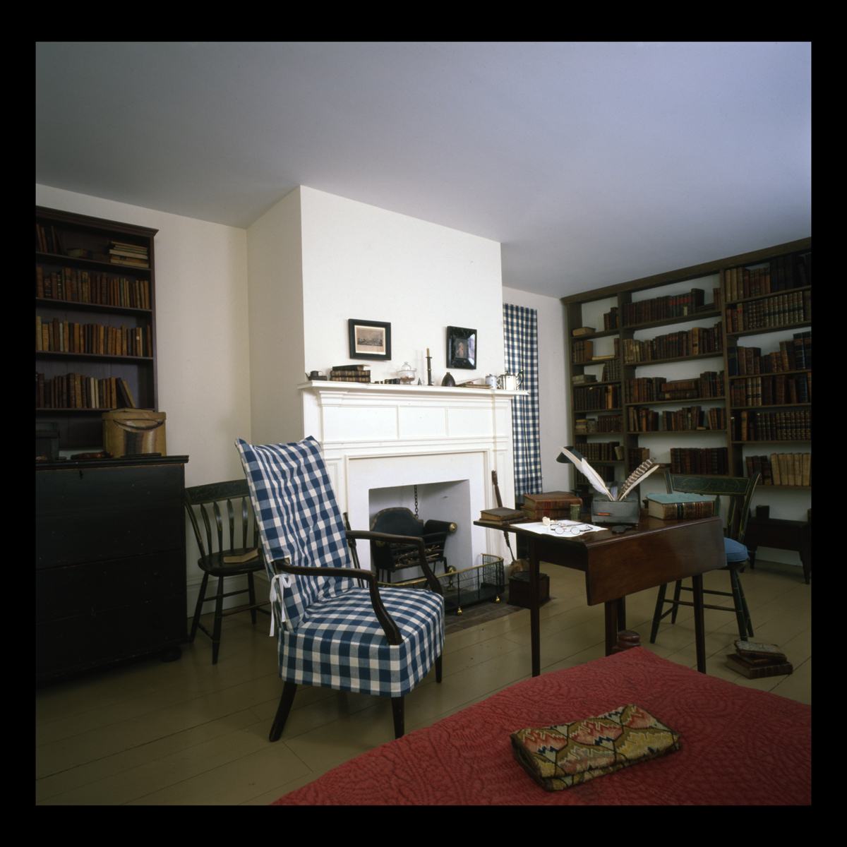 Room containing bookshelves, armchair, and table and side chairs