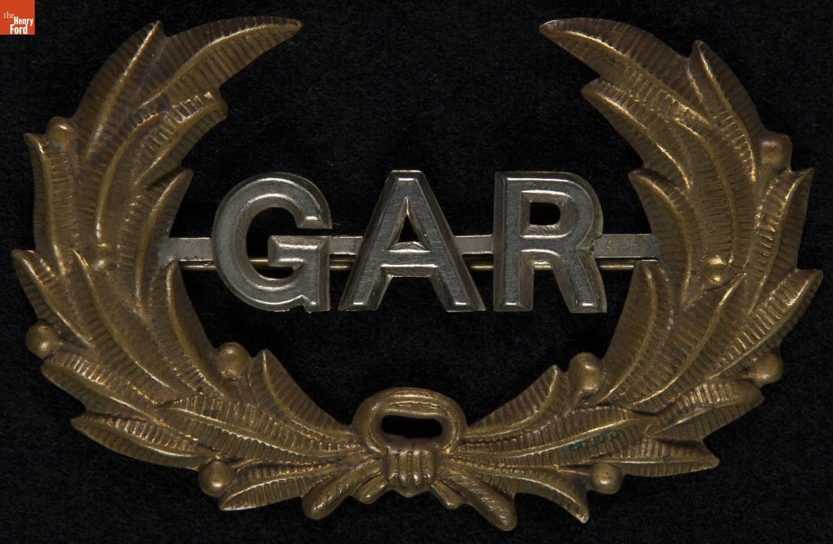 Metal pin with gold laurel and silver letters "GAR"