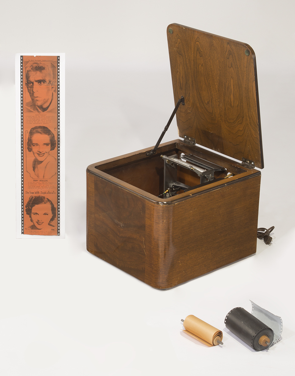 Crosley Reado Radio Printer, 1938-1940 Wooden box with machinery inside, paper strip with images of three faces, paper reels