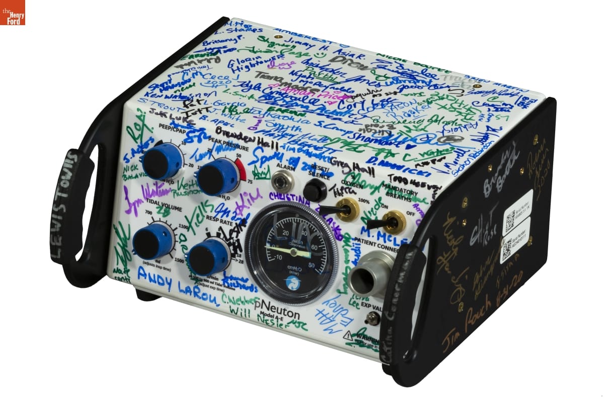 Piece of white machinery with black handles and dials and knobs on the front; covered in people's signatures in various colors
