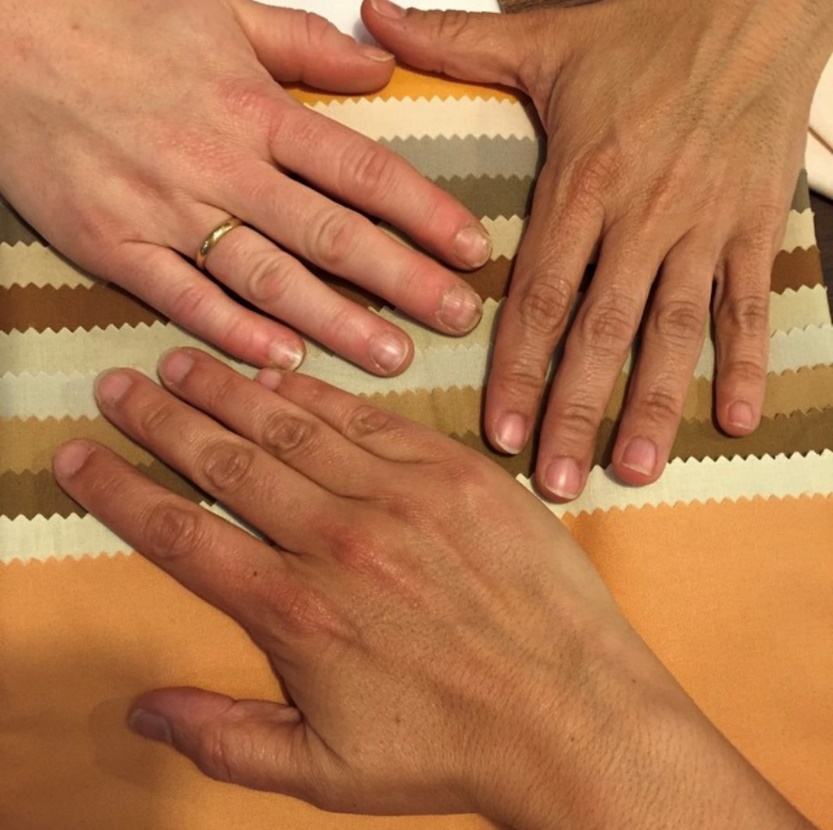 Three hands of varying skin tones