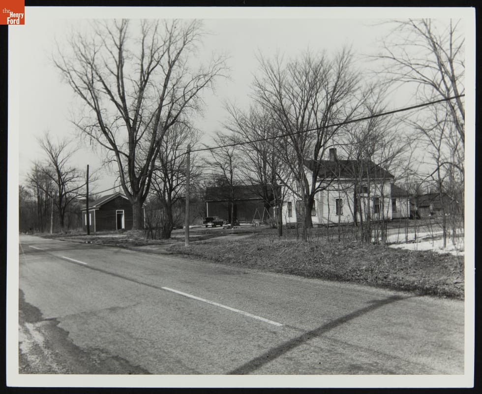 Three buildings among trees along a road
