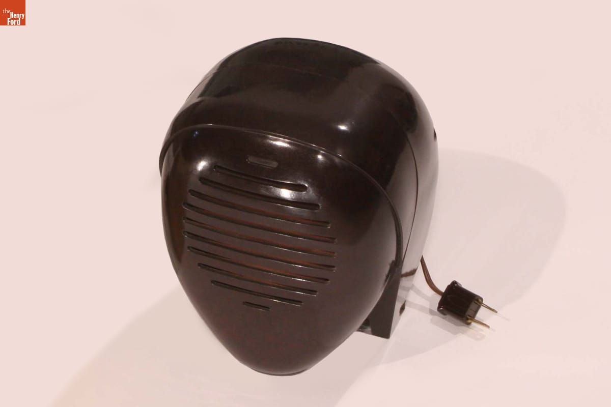 Brown teardrop shaped device with plug and grille on front