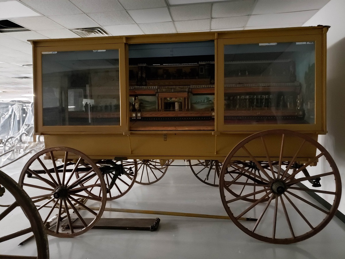 Yellow wagon with glass windows revealing scenes on side